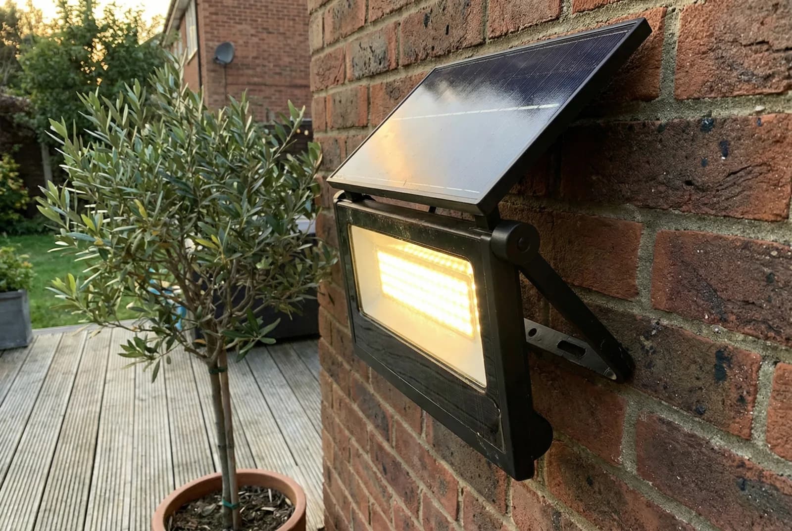 Solar wall light mounted on a brick wall illuminating a patio area